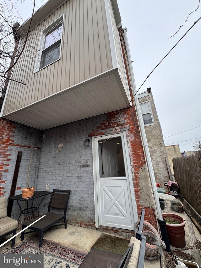rear view of property with brick siding and fence