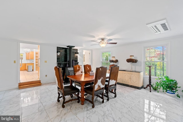 dining space featuring visible vents, baseboards, crown molding, ceiling fan with notable chandelier, and marble finish floor