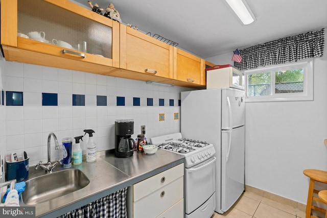 kitchen featuring light tile patterned floors, tasteful backsplash, stainless steel counters, gas range gas stove, and a sink