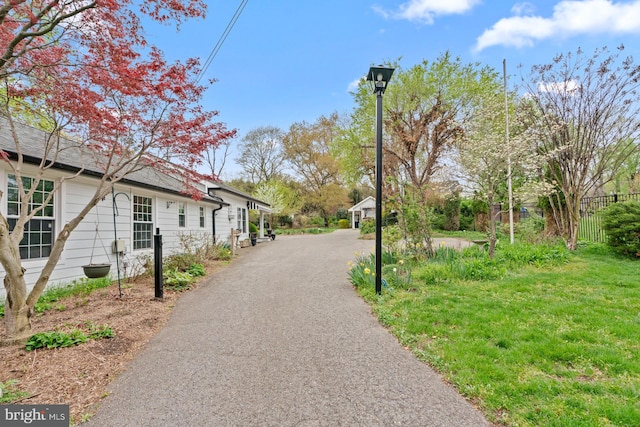 view of community featuring driveway, fence, and a lawn