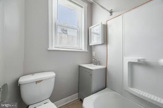 bathroom with a tub, vanity, toilet, a shower, and baseboards