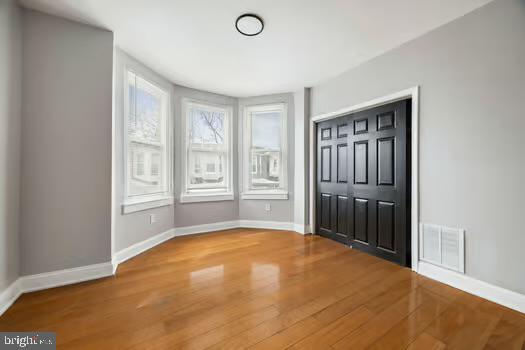 interior space with wood finished floors, baseboards, and visible vents