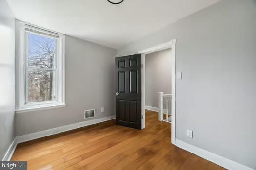 unfurnished room with visible vents, baseboards, and wood finished floors