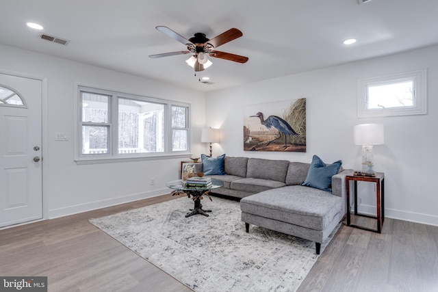 living room with a wealth of natural light, visible vents, a ceiling fan, and wood finished floors