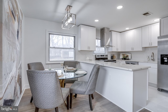 kitchen featuring visible vents, exhaust hood, a sink, white cabinetry, and stainless steel appliances