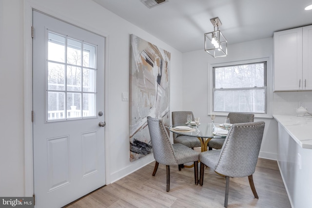dining space featuring light wood-style flooring, baseboards, and visible vents