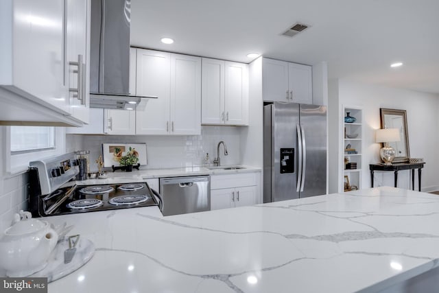 kitchen featuring visible vents, wall chimney exhaust hood, a sink, appliances with stainless steel finishes, and white cabinetry