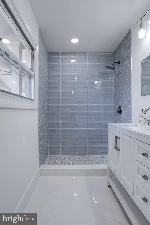bathroom with a tile shower and vanity