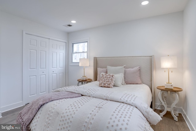 bedroom featuring wood finished floors, baseboards, a closet, and visible vents