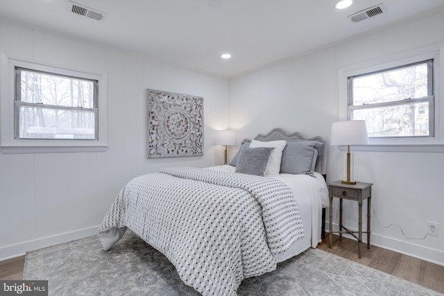 bedroom with wood finished floors, multiple windows, and visible vents