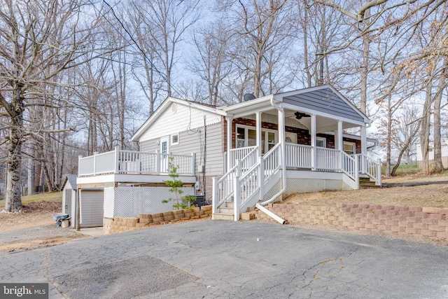 view of front facade featuring a porch, ceiling fan, aphalt driveway, and stairway
