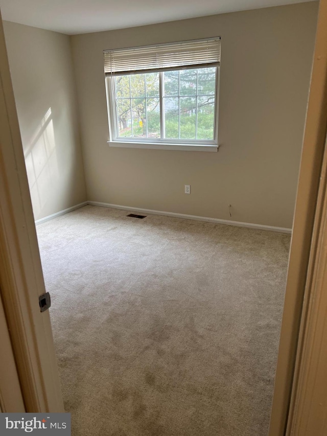 spare room featuring baseboards, visible vents, and carpet floors
