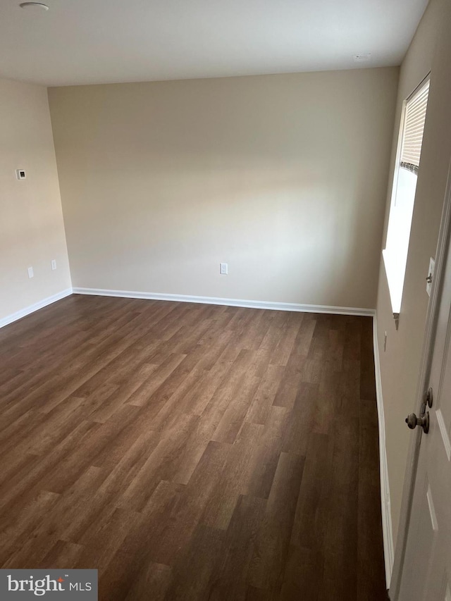 empty room featuring dark wood-type flooring and baseboards