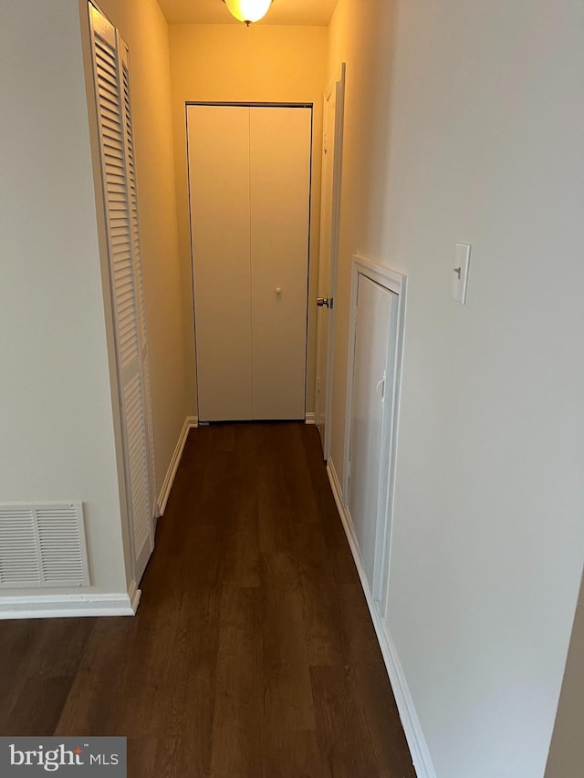 corridor with wood finished floors, baseboards, and visible vents