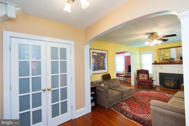 111 Somerset Ave, Cambridge, MD 21613 - living area featuring a ceiling fan, a wood stove, french doors, arched walkways, and dark wood finished floors