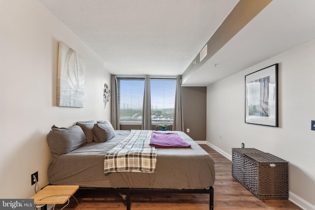 bedroom with visible vents, baseboards, and wood finished floors