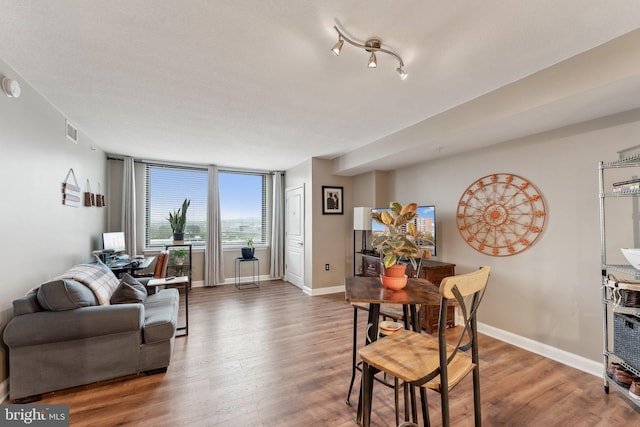 living area with wood finished floors, baseboards, and visible vents