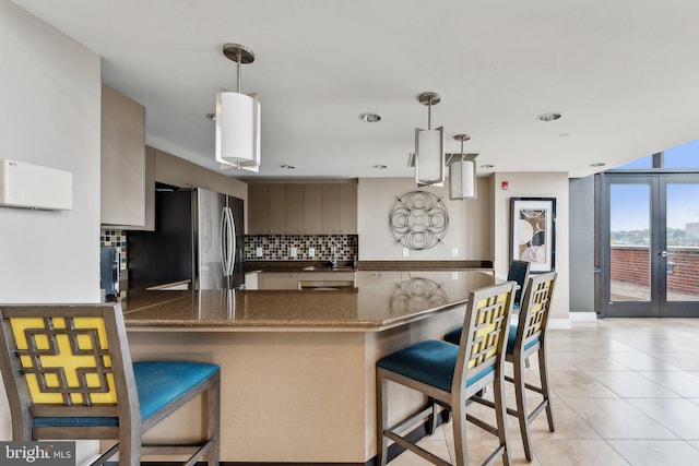 kitchen with tasteful backsplash, freestanding refrigerator, a peninsula, french doors, and a breakfast bar area