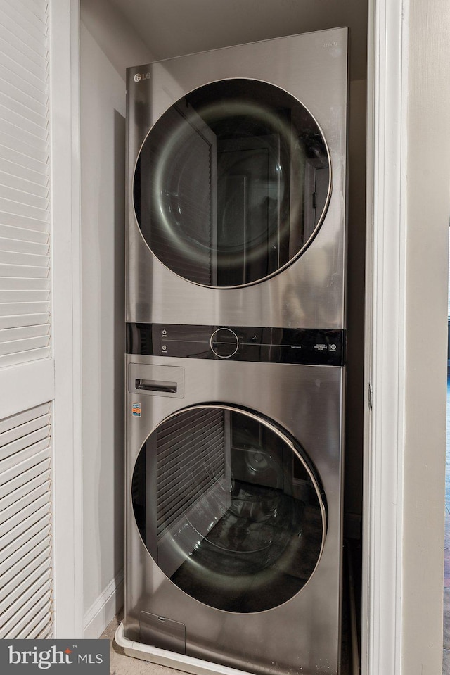 laundry room featuring laundry area, stacked washer and dryer, and baseboards