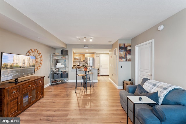living area with visible vents, light wood-type flooring, and baseboards