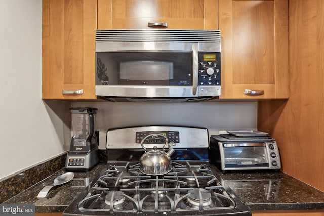 kitchen featuring dark stone countertops, a toaster, and stainless steel appliances