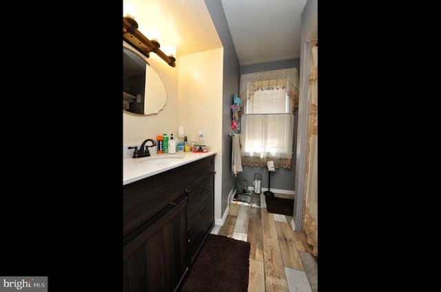 full bathroom with vanity, baseboards, and wood finished floors