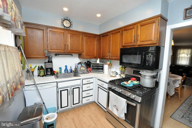 kitchen with dishwasher, light countertops, stainless steel range with gas cooktop, brown cabinetry, and black microwave