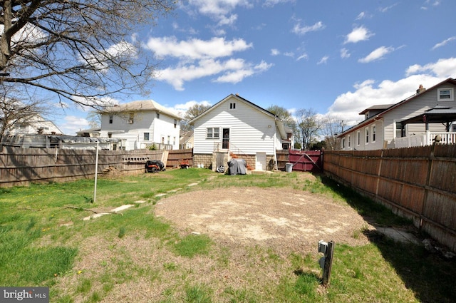 back of property with a fenced backyard and a lawn