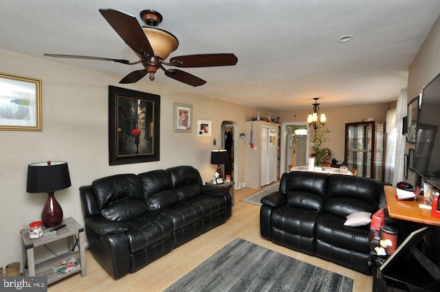 living area with ceiling fan with notable chandelier and wood finished floors