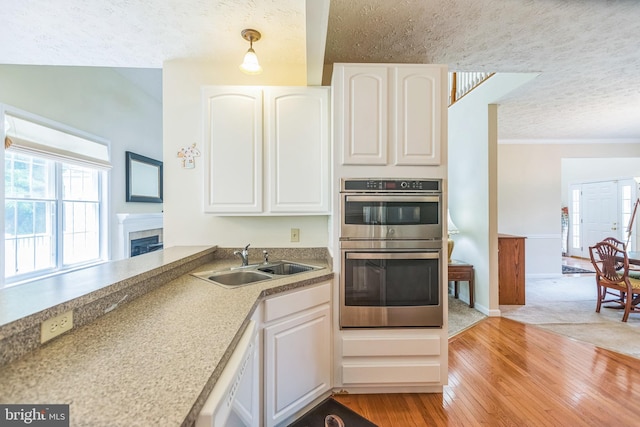 8900 Leonardo St, Pomfret, MD 20675 - kitchen featuring a sink, double oven, a textured ceiling, white dishwasher, and white cabinetry