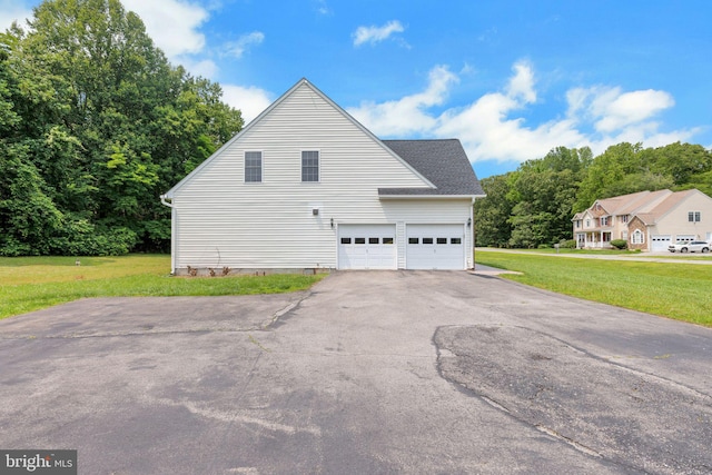 8900 Leonardo St, Pomfret, MD 20675 - view of side of home with a garage, a lawn, and asphalt driveway