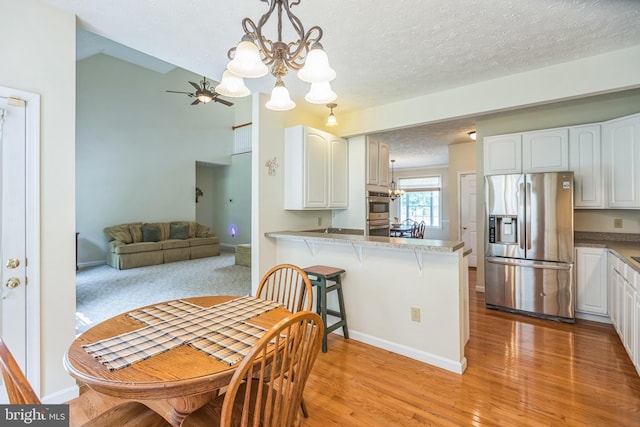 8900 Leonardo St, Pomfret, MD 20675 - dining space with a chandelier, light wood finished floors, a ceiling fan, baseboards, and a textured ceiling