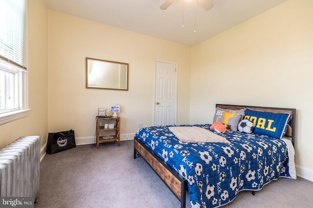 carpeted bedroom with radiator heating unit, baseboards, and a ceiling fan