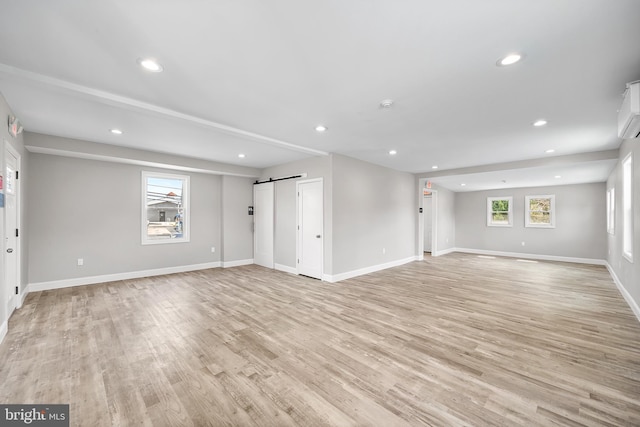 interior space with light wood-style floors, recessed lighting, baseboards, and a barn door