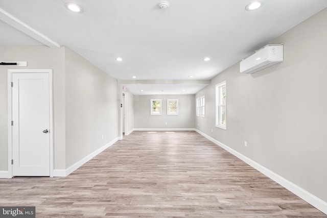 empty room with an AC wall unit, baseboards, recessed lighting, and light wood-style floors