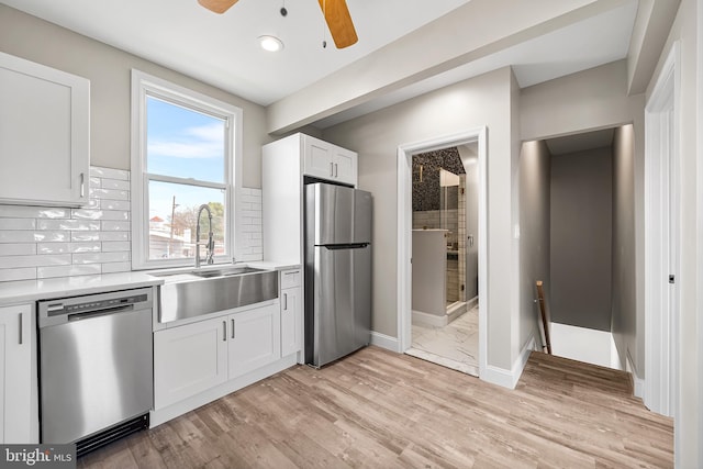 kitchen featuring appliances with stainless steel finishes, light countertops, backsplash, ceiling fan, and a sink