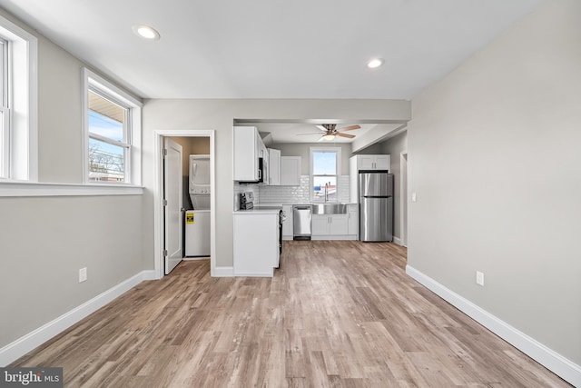kitchen featuring backsplash, a ceiling fan, stacked washing maching and dryer, stainless steel appliances, and a sink