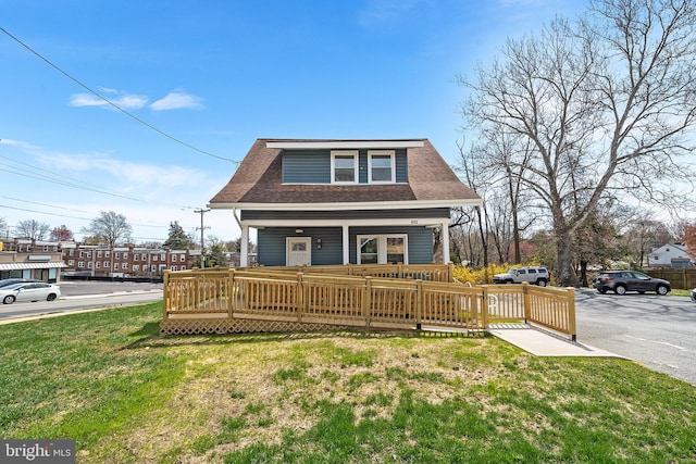 view of front of house with roof with shingles, fence, a front lawn, and covered porch