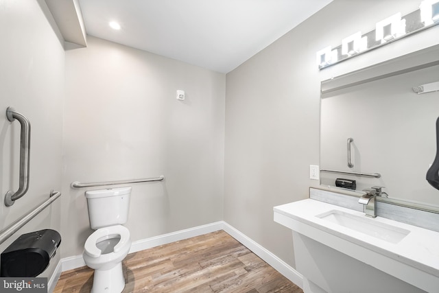 bathroom with toilet, wood finished floors, a sink, and baseboards