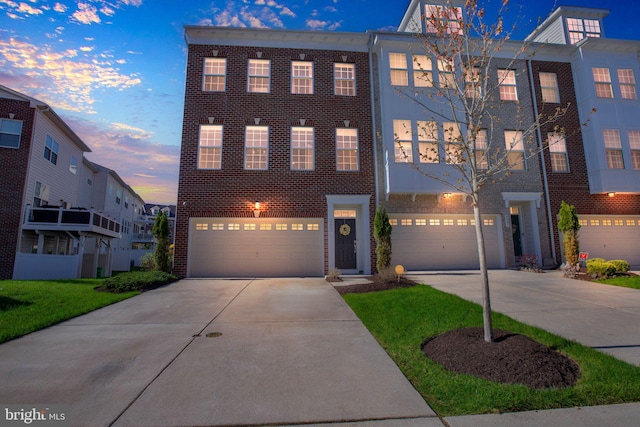 townhome / multi-family property with concrete driveway, brick siding, and an attached garage
