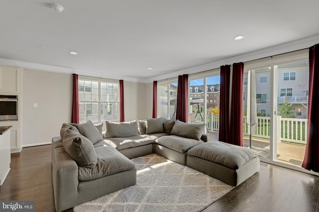living area featuring dark wood-type flooring, ornamental molding, and plenty of natural light