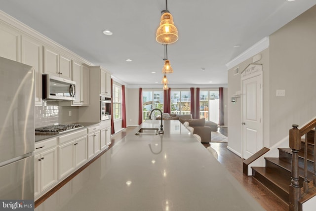 kitchen with tasteful backsplash, hanging light fixtures, open floor plan, stainless steel appliances, and baseboards