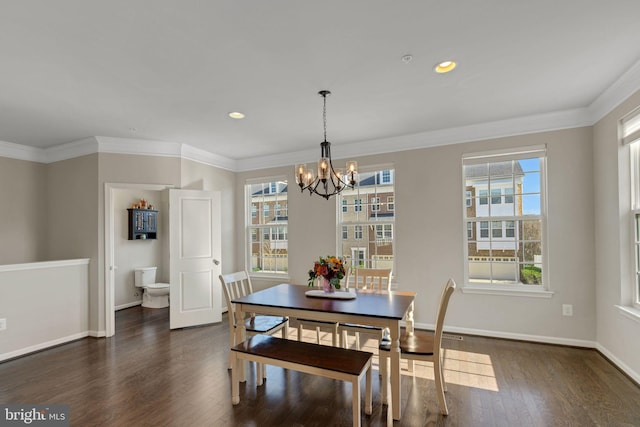 dining room with dark wood-type flooring, ornamental molding, baseboards, and an inviting chandelier