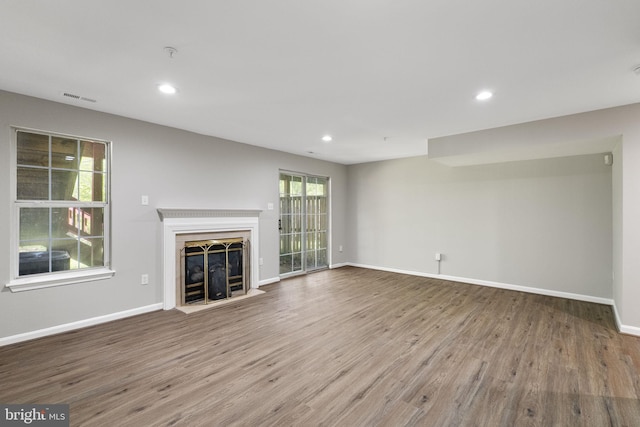 unfurnished living room with recessed lighting, wood finished floors, a fireplace, baseboards, and visible vents