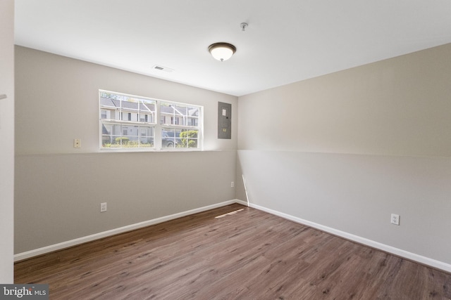 spare room with visible vents, wood finished floors, electric panel, and baseboards