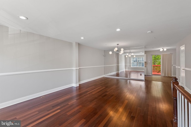 empty room featuring baseboards, a notable chandelier, recessed lighting, and wood-type flooring