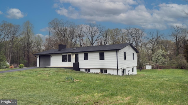 view of front of property featuring a chimney, driveway, a front yard, and a garage