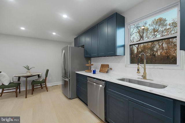 kitchen with recessed lighting, light wood-style flooring, light stone countertops, stainless steel appliances, and a sink