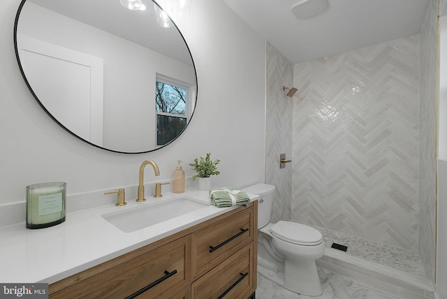bathroom featuring tiled shower, vanity, marble finish floor, and toilet