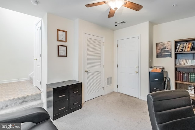 carpeted home office with ceiling fan, baseboards, and visible vents